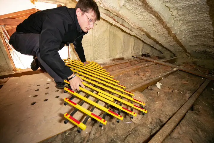 Technician kneeling on boards over attic insulation
