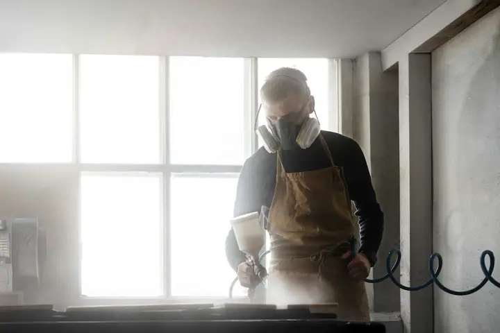 Worker in a respirator and apron preparing equipment