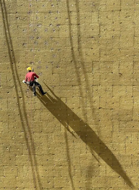 Technician on rope access along an insulated wall